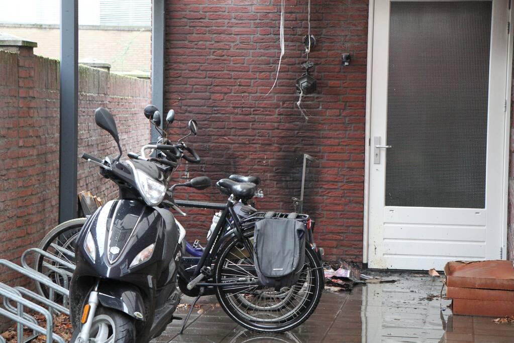 Brand onder overkapping van woning