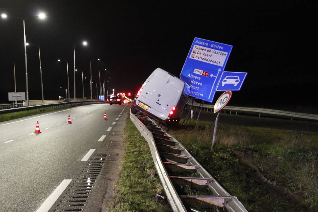 Bestelbus rijdt op vangrail en raakt verkeersborden