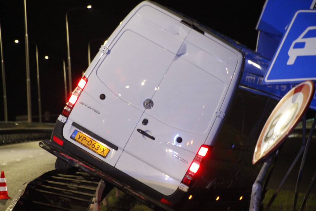 Bestelbus rijdt op vangrail en raakt verkeersborden
