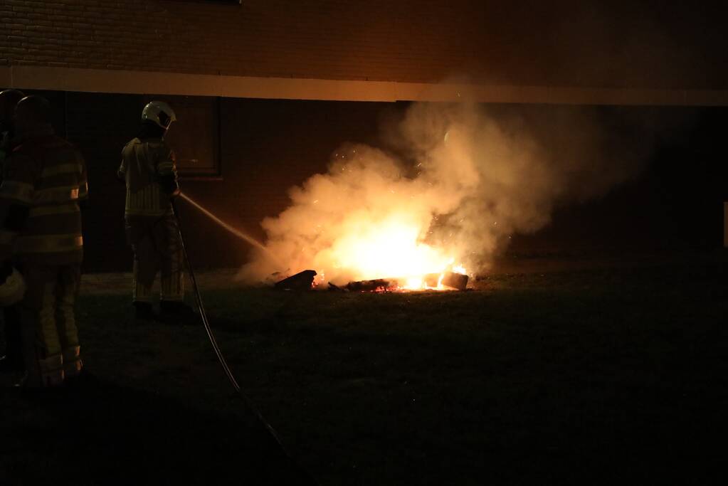 Hout en afval in brand tegen gevel