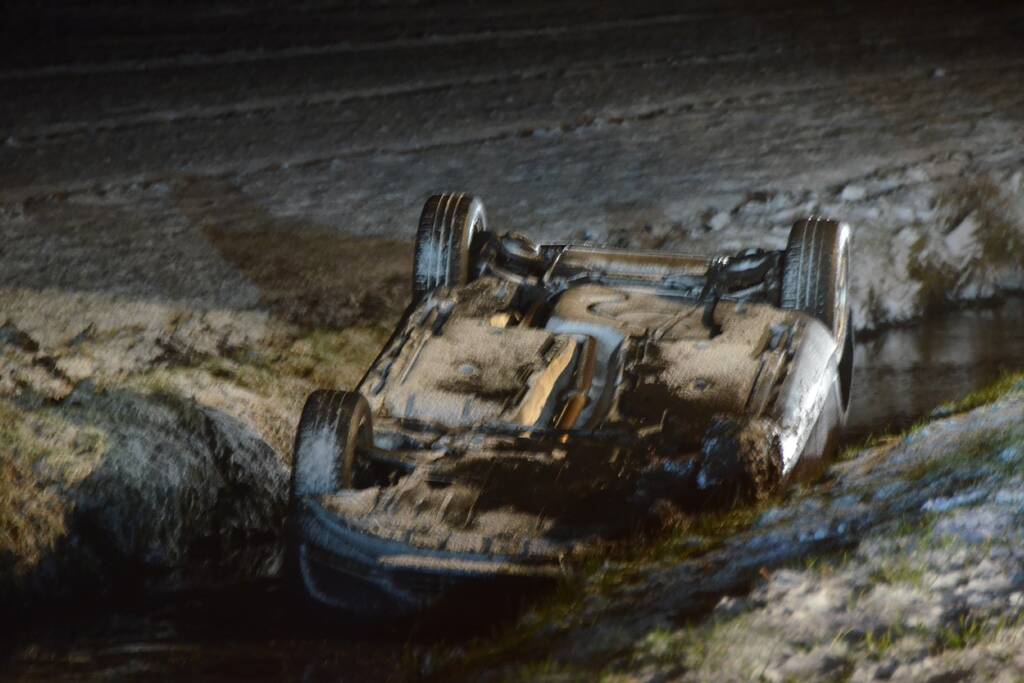 Auto glijdt van de weg en belandt op de kop in sloot
