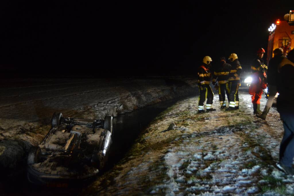 Auto glijdt van de weg en belandt op de kop in sloot