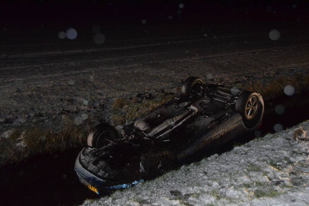 Auto glijdt van de weg en belandt op de kop in sloot