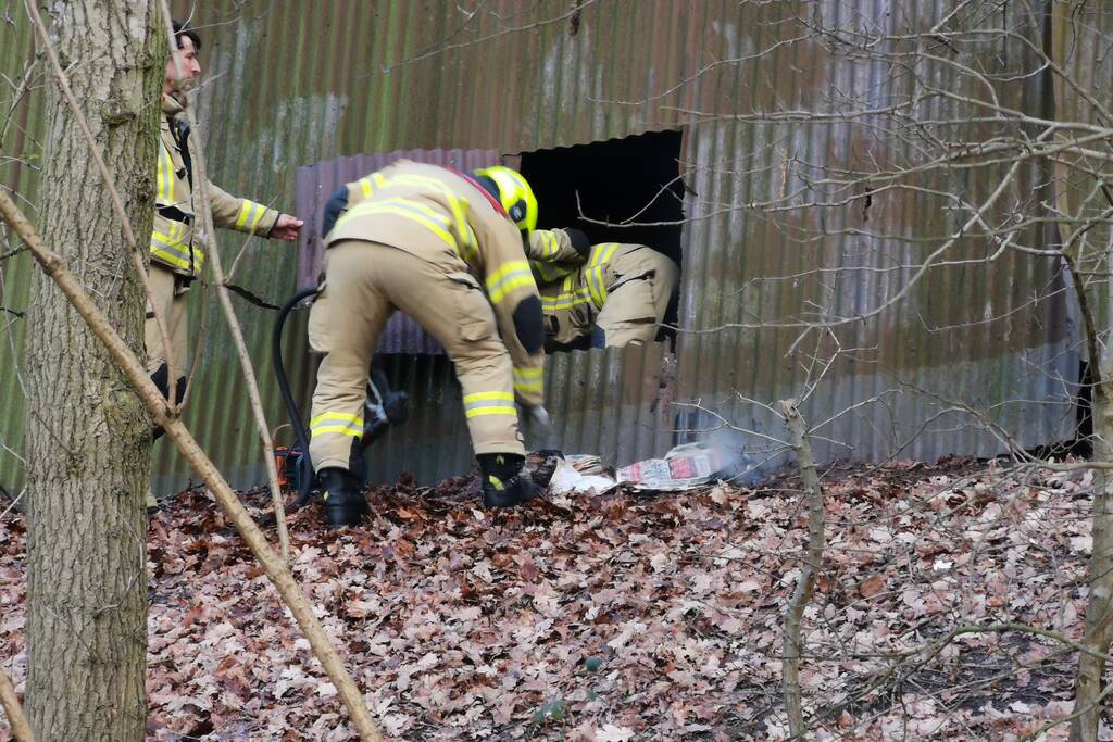Brandweer blust brand in muur van golfplaten
