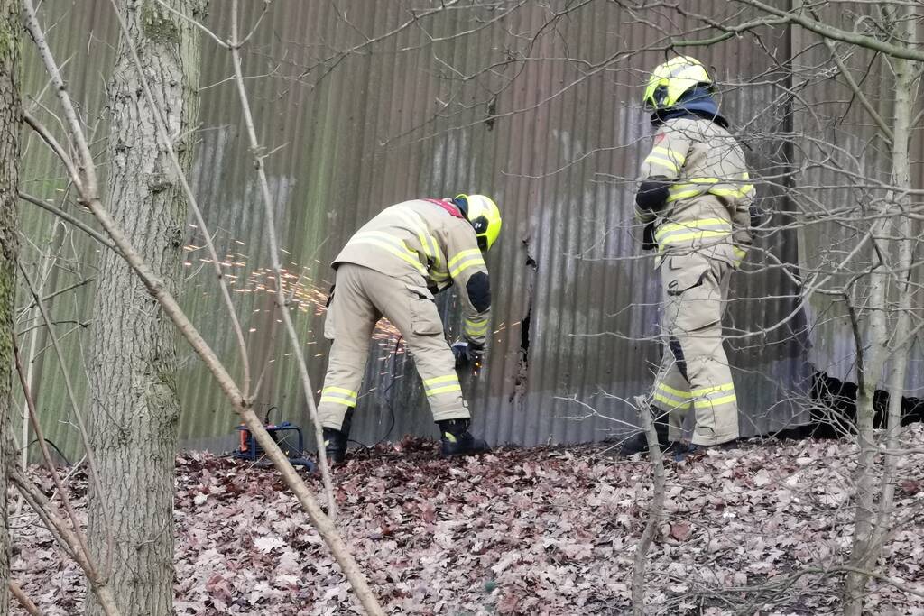 Brandweer blust brand in muur van golfplaten
