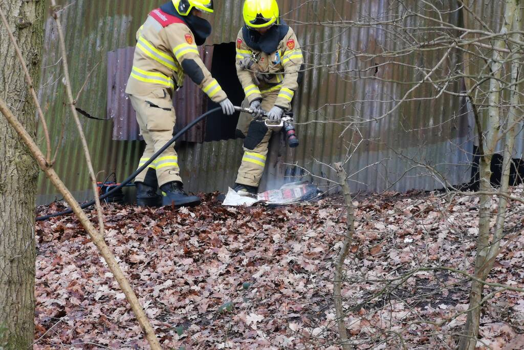 Brandweer blust brand in muur van golfplaten