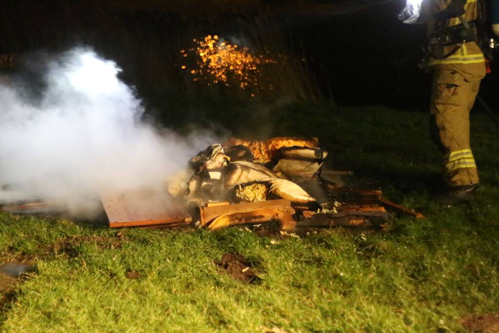 Brandweer blust brandende matras en pallets