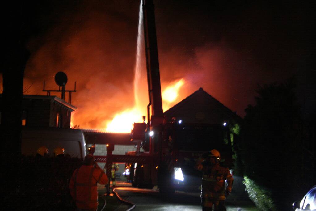 Grote uitslaande brand in loods achter woning
