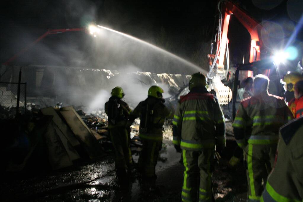 Grote uitslaande brand in loods achter woning