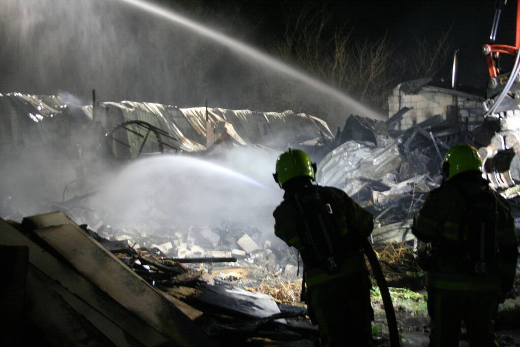 Grote uitslaande brand in loods achter woning