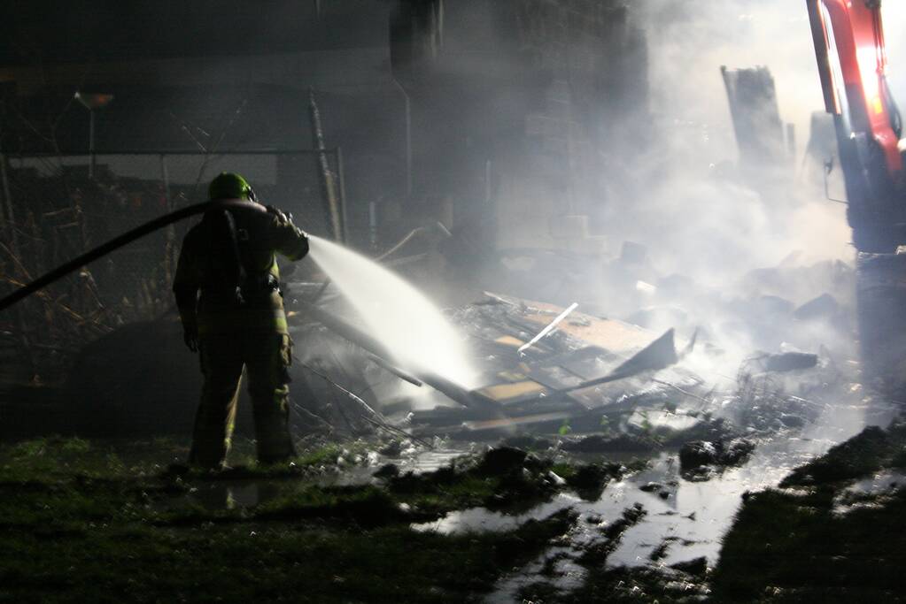 Grote uitslaande brand in loods achter woning