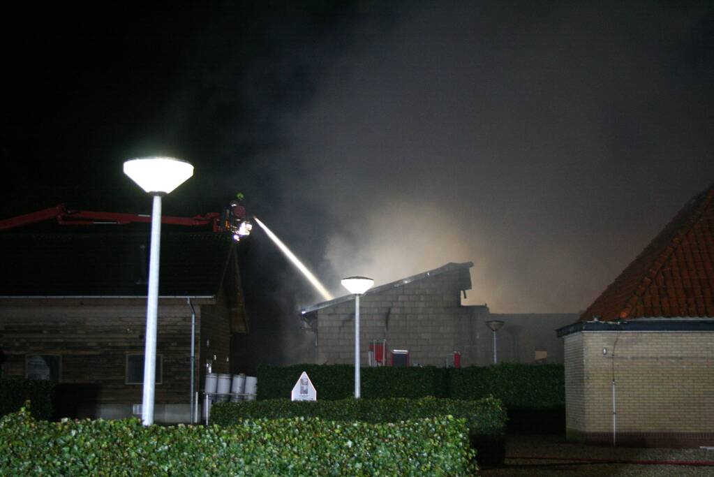 Grote uitslaande brand in loods achter woning