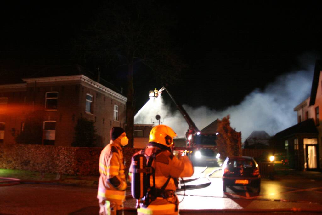 Grote uitslaande brand in loods achter woning