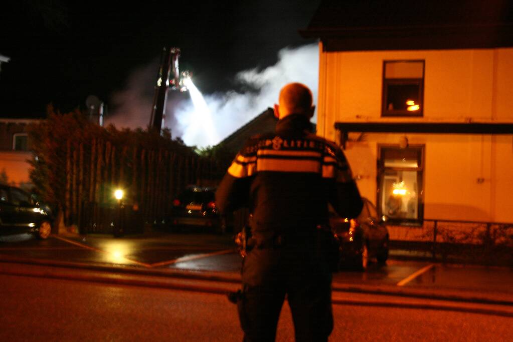 Grote uitslaande brand in loods achter woning
