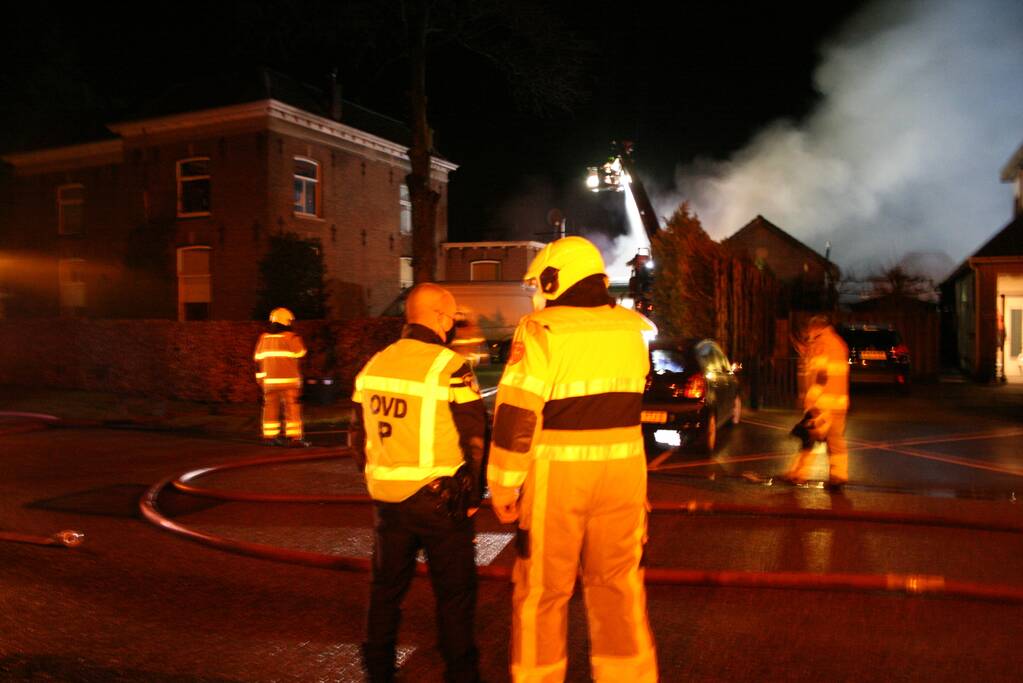 Grote uitslaande brand in loods achter woning
