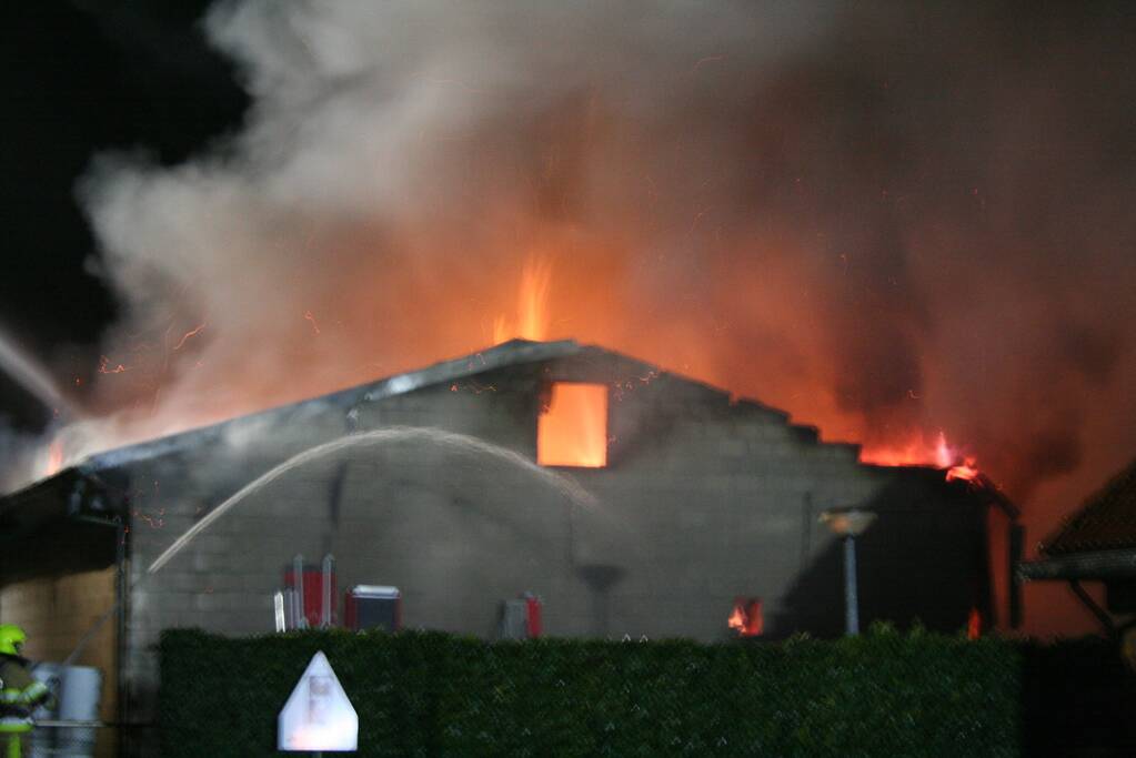 Grote uitslaande brand in loods achter woning
