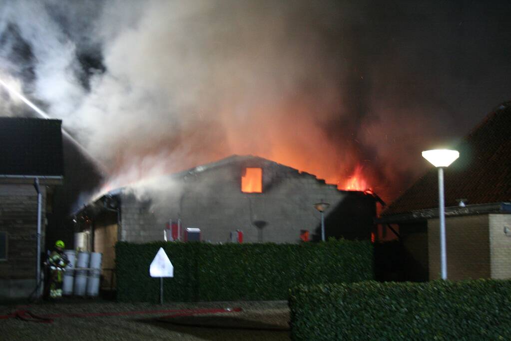 Grote uitslaande brand in loods achter woning