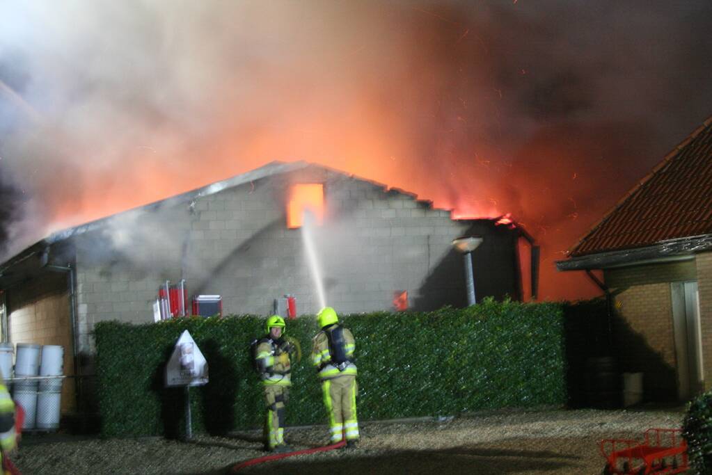 Grote uitslaande brand in loods achter woning