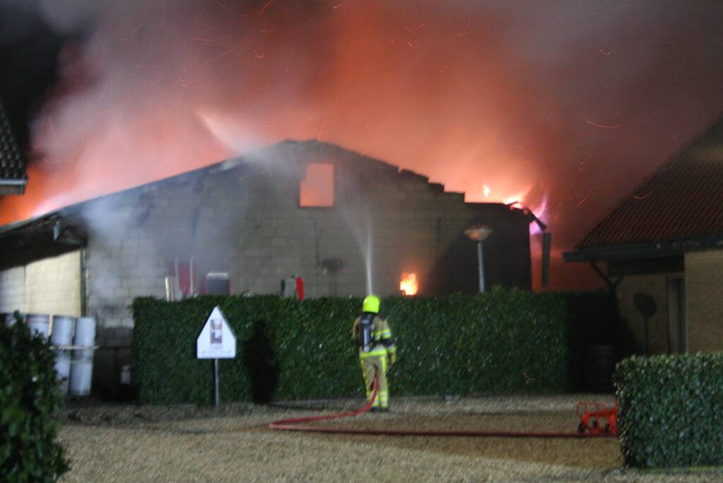 Grote uitslaande brand in loods achter woning