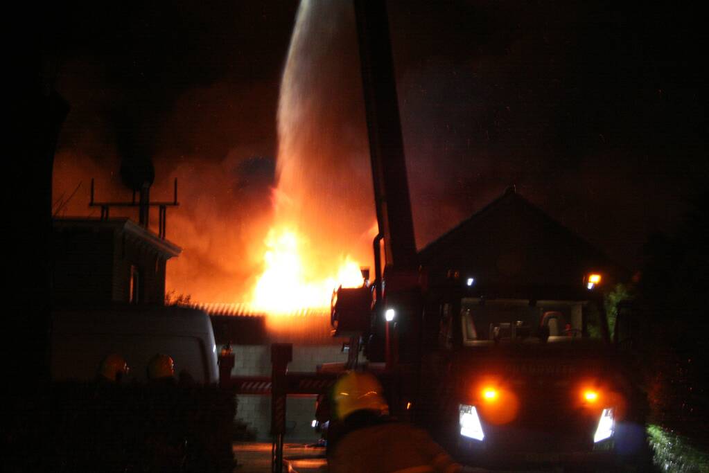 Grote uitslaande brand in loods achter woning