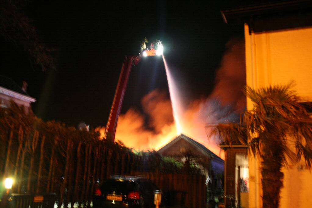 Grote uitslaande brand in loods achter woning