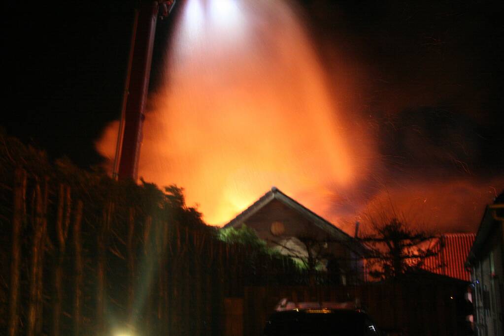 Grote uitslaande brand in loods achter woning