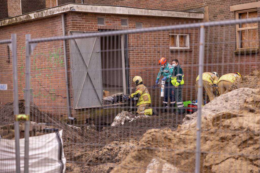 Persoon bekneld onder betonnen plaat