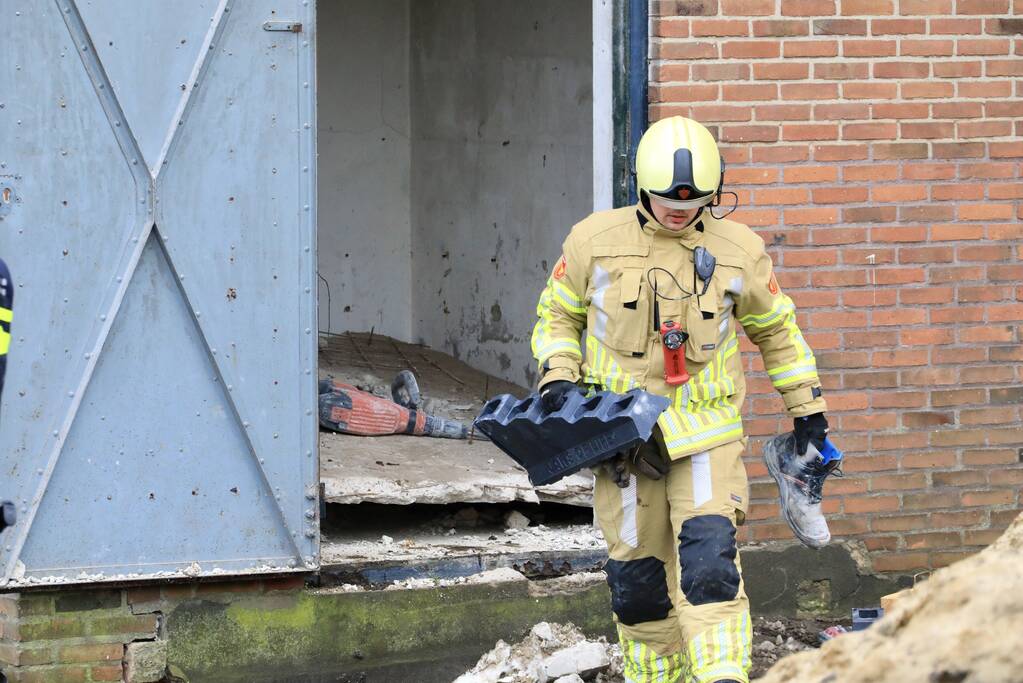 Persoon bekneld onder betonnen plaat