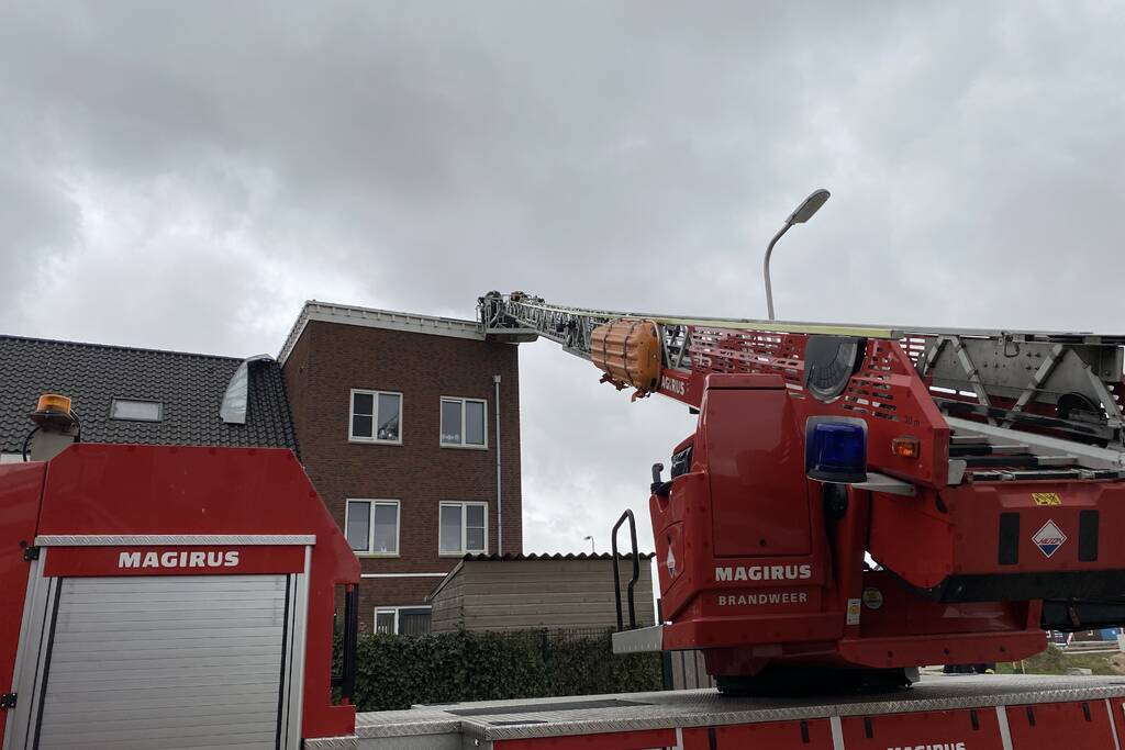 Brandweer haalt losgewaaide platen van dak