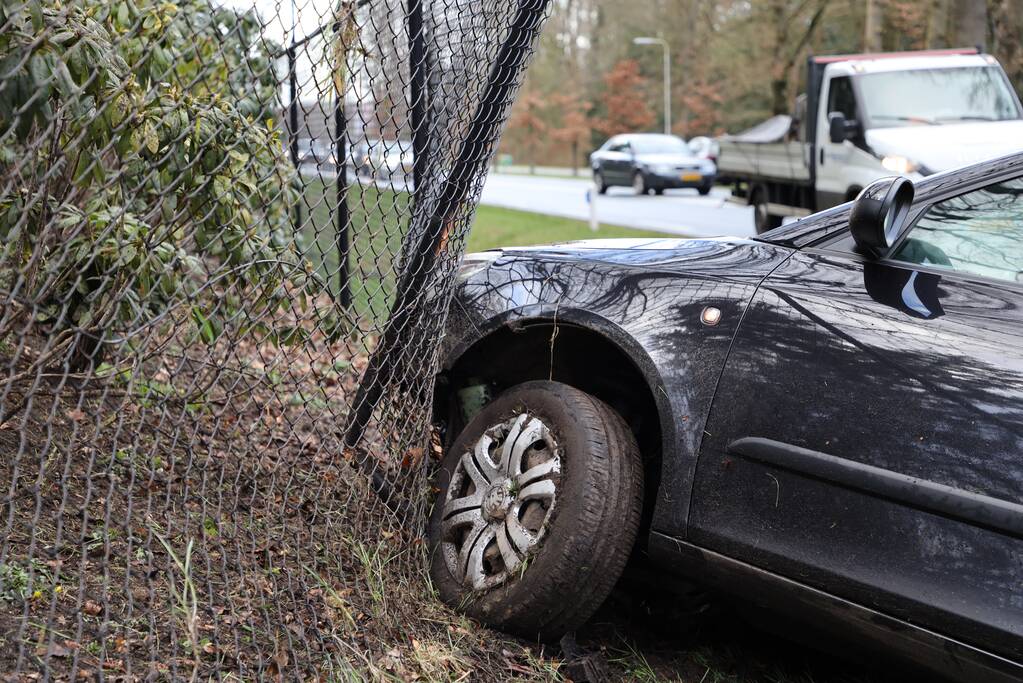 Auto eindigt aan overkant van de weg in hekwerk