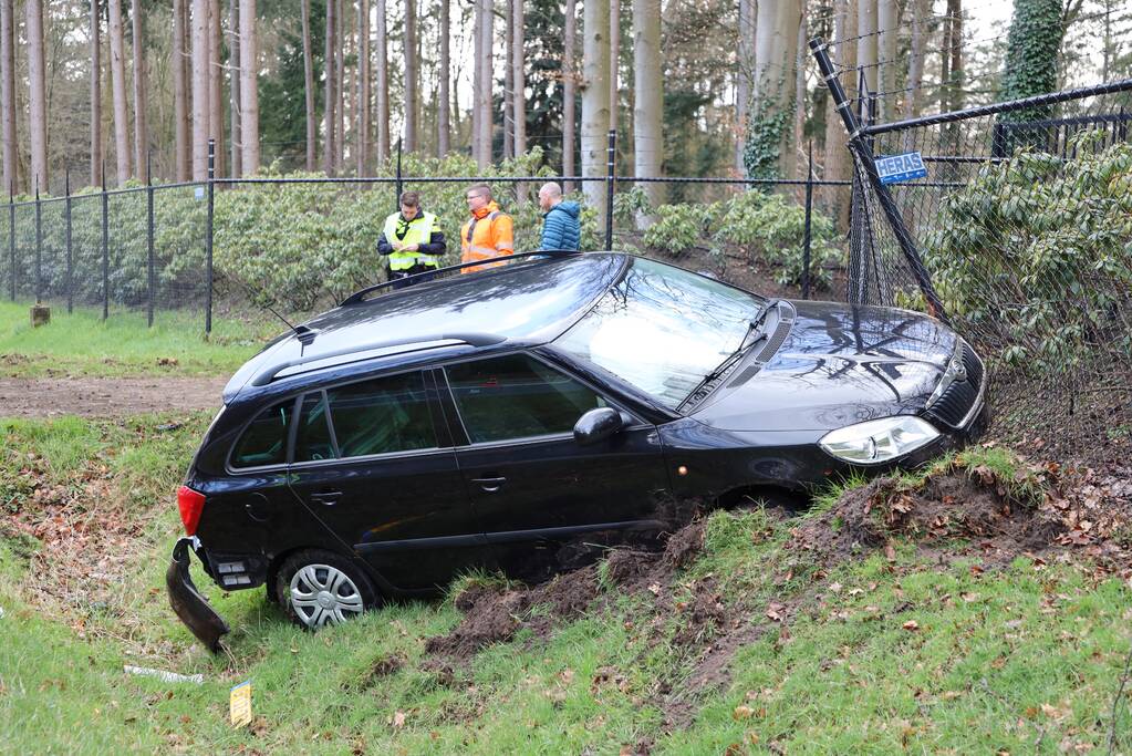 Auto eindigt aan overkant van de weg in hekwerk