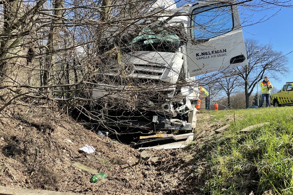 Vrachtwagen belandt in berm tegen boom