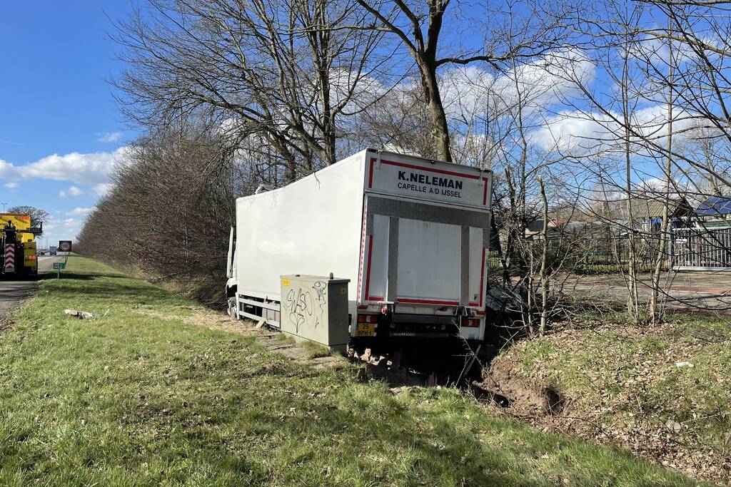 Vrachtwagen belandt in berm tegen boom