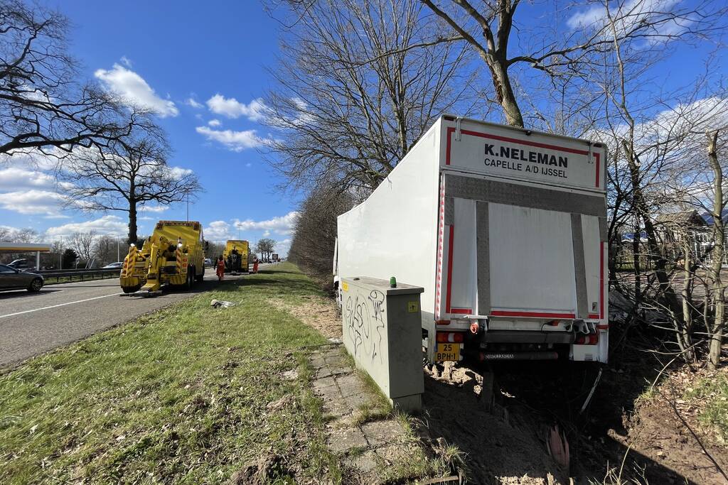 Vrachtwagen belandt in berm tegen boom
