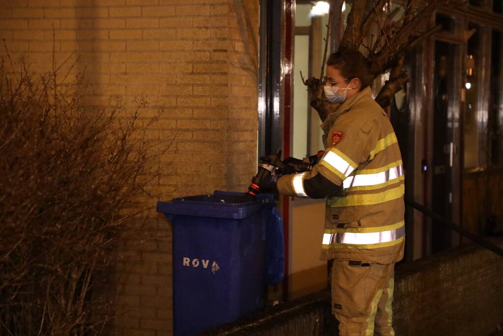 Brandweer blust brandende papiercontainer