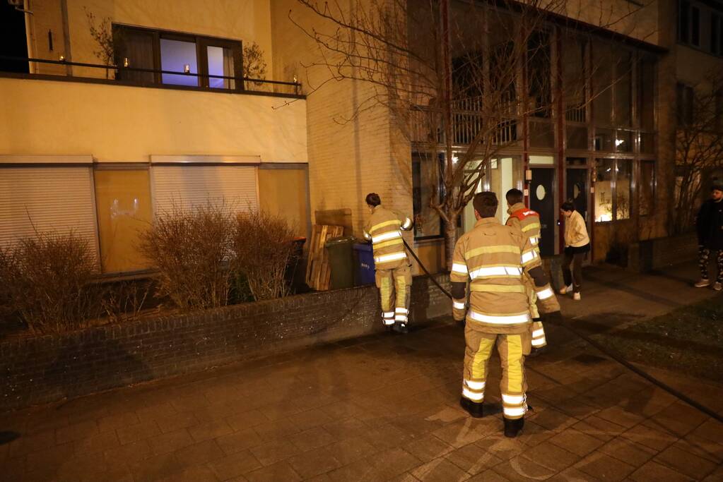 Brandweer blust brandende papiercontainer