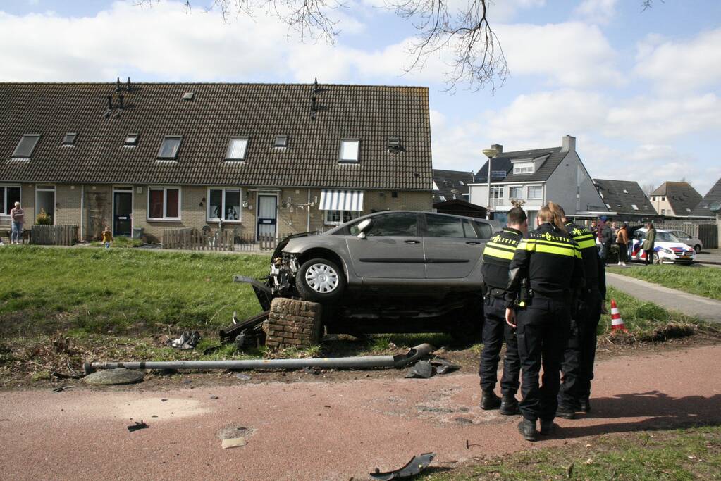 Auto botst op betonblok met lantaarnpaal