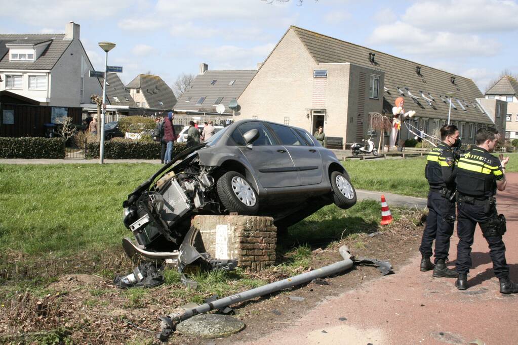 Auto botst op betonblok met lantaarnpaal