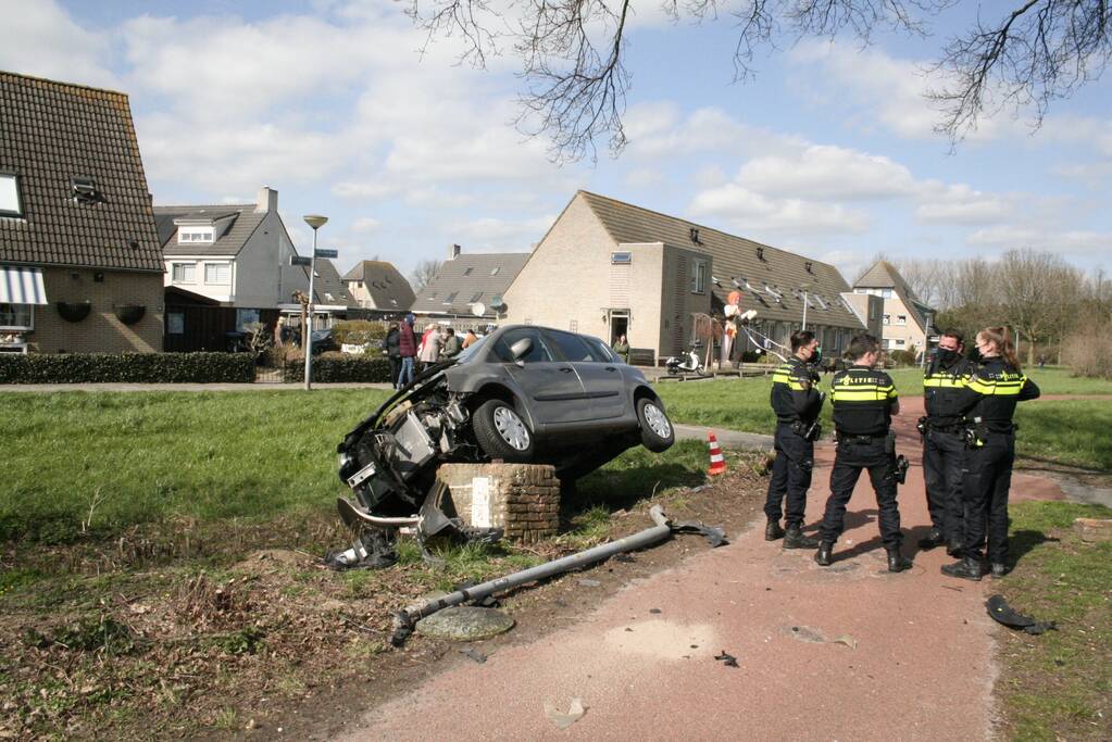 Auto botst op betonblok met lantaarnpaal