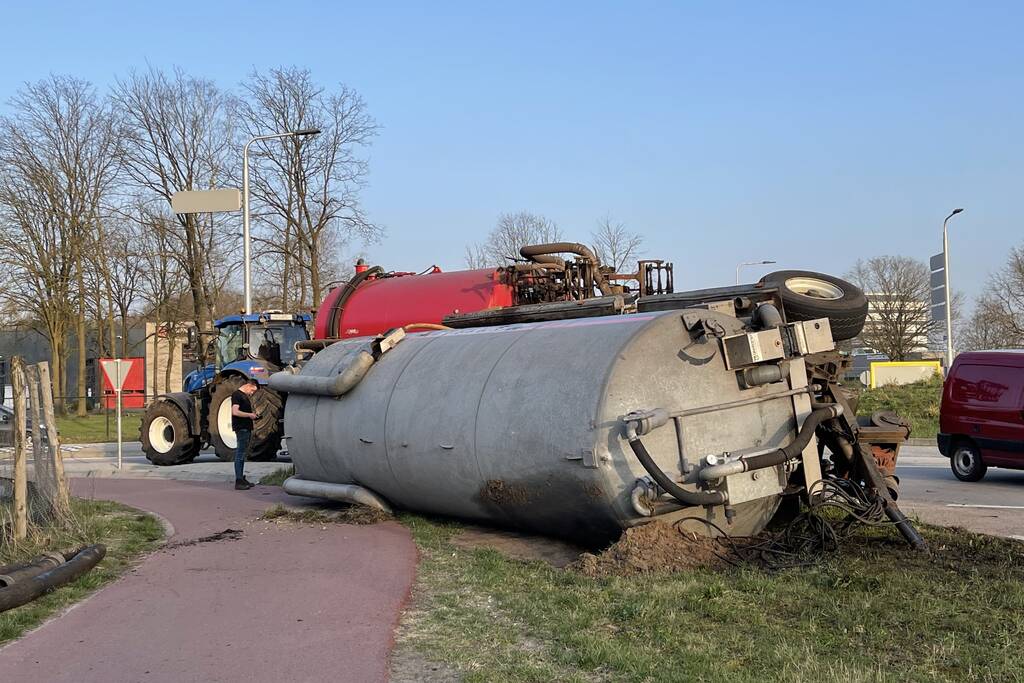Giertank met mest gekanteld op rotonde