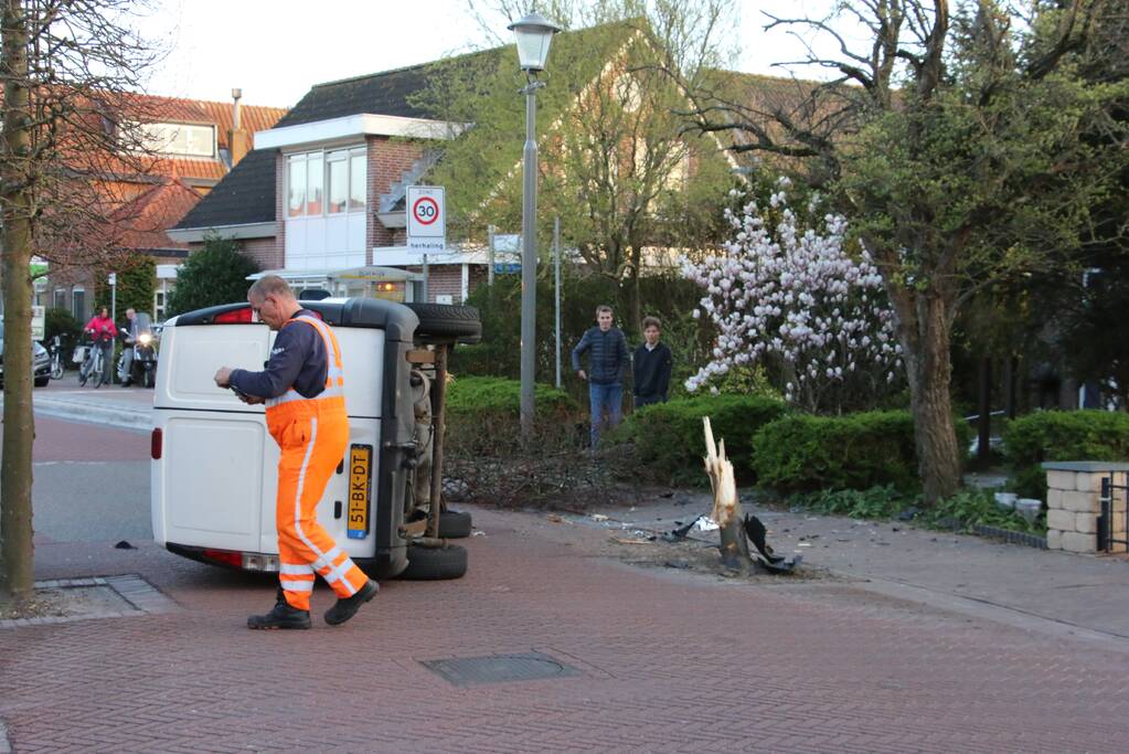 Busje op zijn kant na botsing met boom