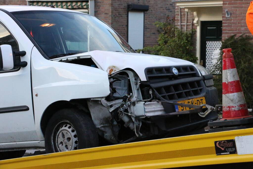 Busje op zijn kant na botsing met boom