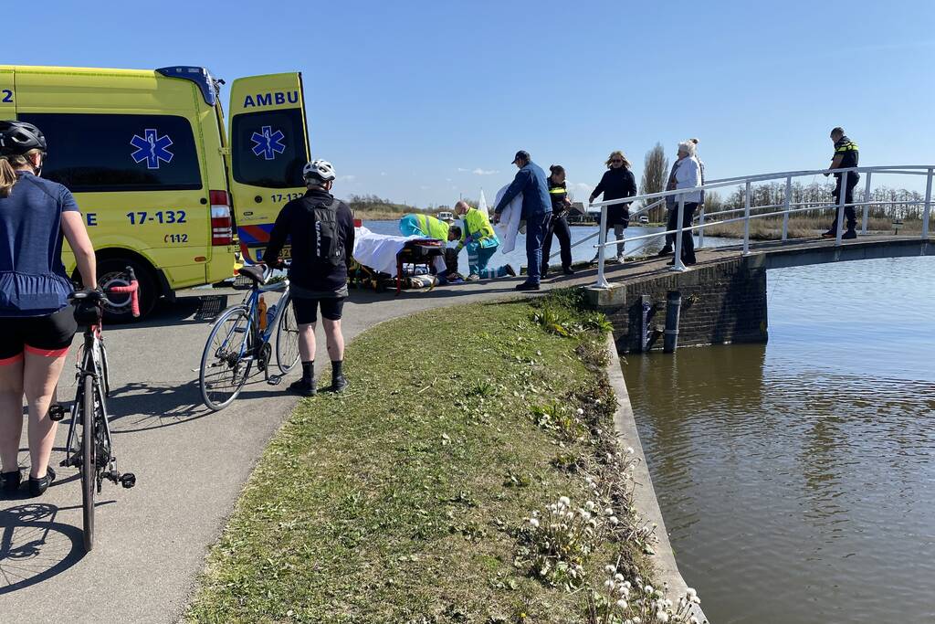 Vrouw kukelt met fiets van brug