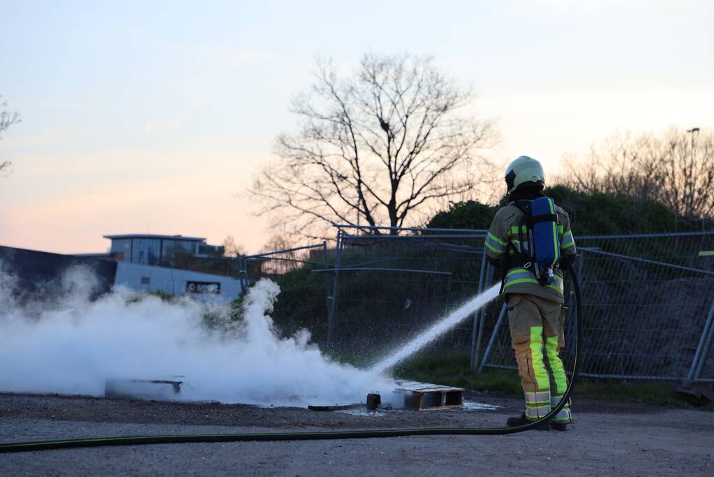 Brandweer blust brandende pallets