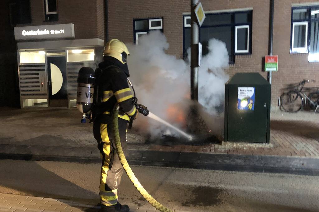 Houtstapel in brand naast container