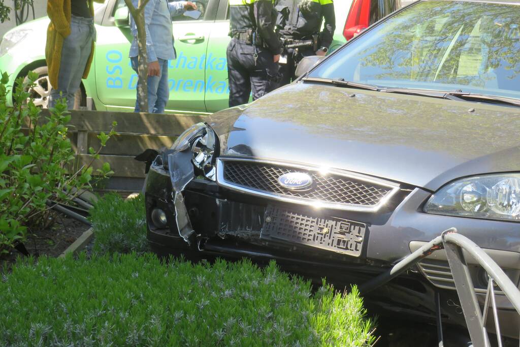 Bestuurder rijdt met auto op tuinhek