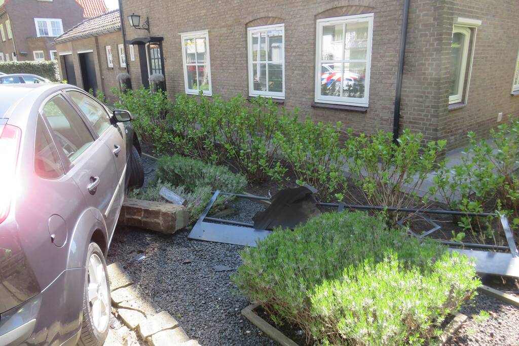 Bestuurder rijdt met auto op tuinhek