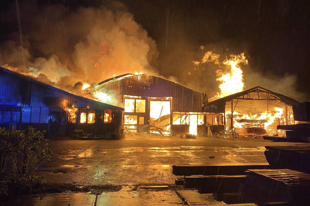 Brandweer bestrijdt grote uitslaande brand in twee loodsen
