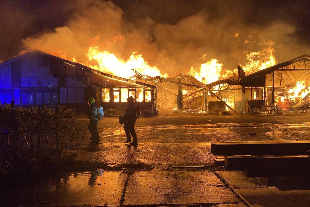 Brandweer bestrijdt grote uitslaande brand in twee loodsen