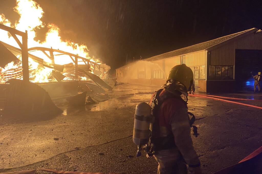 Brandweer bestrijdt grote uitslaande brand in twee loodsen